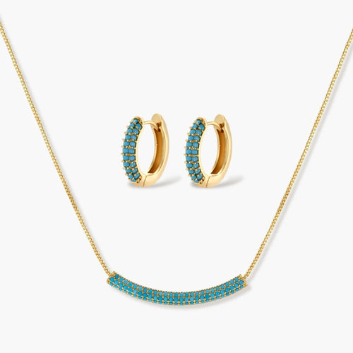 Gold-plated curved necklace and hoop earrings with turquoise cubic zirconia stones on white background.