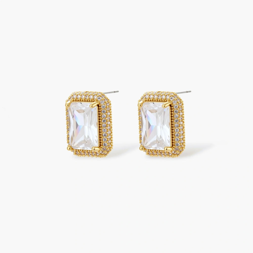 Gold-plated jewelry set with rectangular cubic zirconia stones in pave halo settings on cream background