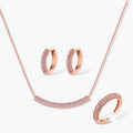 Rose gold pavé zirconia bar necklace, hoop earrings, and open ring set with pink stones on cream background.