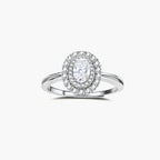 Sterling silver ring with oval moissanite center stone surrounded by double halo of sparkling stones on neutral background.