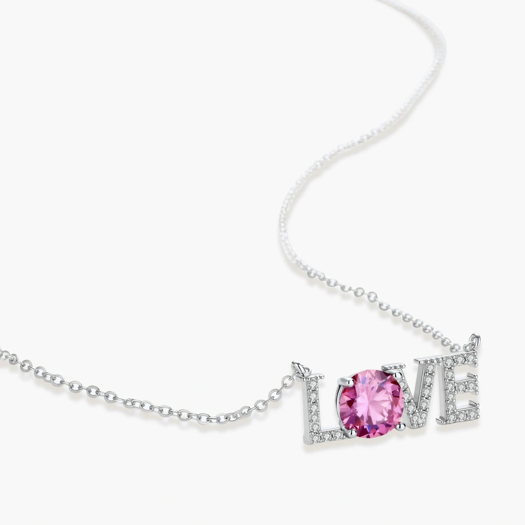 Sterling silver LOVE necklace with pink moissanite stone replacing the O, featuring crystal-set letters on delicate chain.