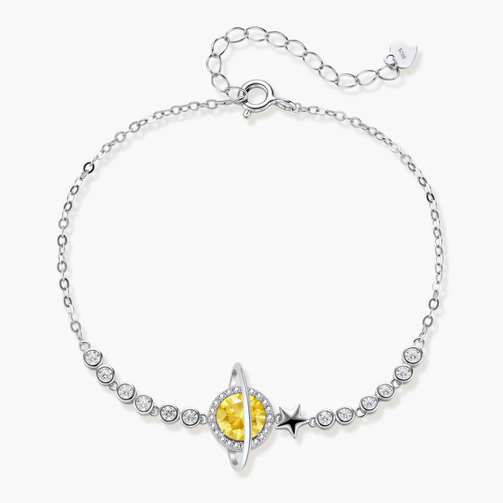 Sterling silver bracelet with yellow moissanite centerpiece in oval setting, crystal chain, and star charm on white background.
