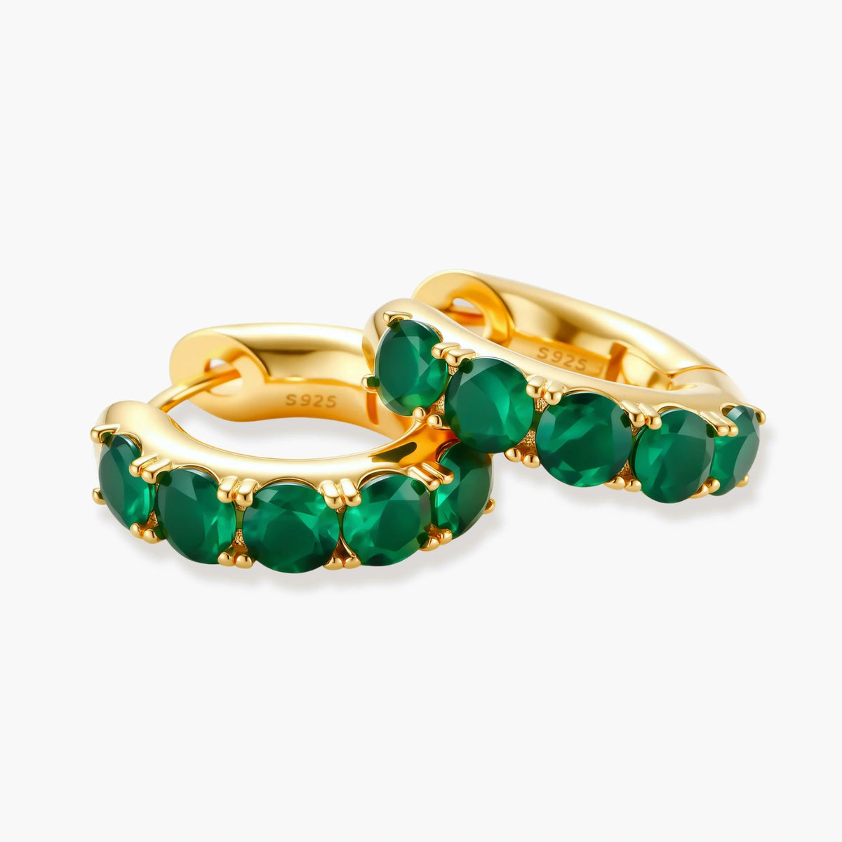 Close-up of gold-plated huggie hoop earrings featuring four emerald green cubic zirconia stones on white background.