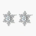 Sterling silver snowflake stud earrings with brilliant moissanite centers and intricate geometric patterns on cream background