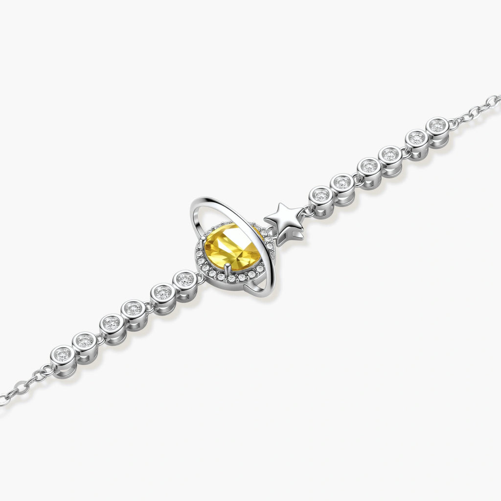 Sterling silver bracelet with yellow moissanite centerpiece in oval setting, crystal chain, and star charm on white background.
