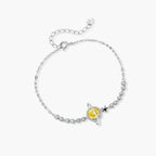 Sterling silver bracelet with yellow moissanite centerpiece in oval setting, crystal chain, and star charm on white background.