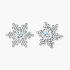 Sterling silver snowflake stud earrings with brilliant moissanite centers and intricate geometric patterns on cream background