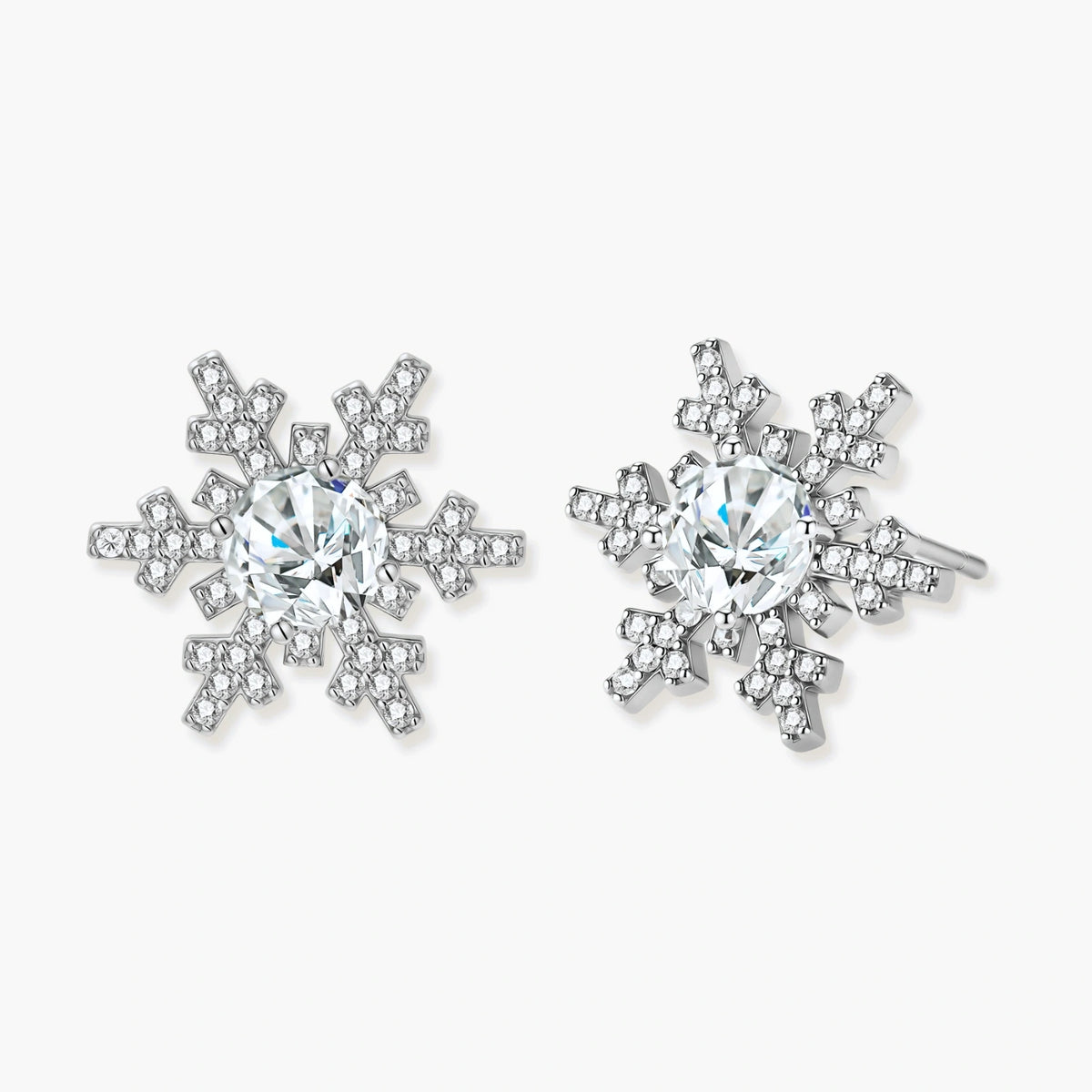 Sterling silver snowflake stud earrings with brilliant moissanite centers and intricate geometric patterns on cream background