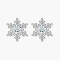 Sterling silver snowflake stud earrings with brilliant moissanite centers and intricate geometric patterns on cream background