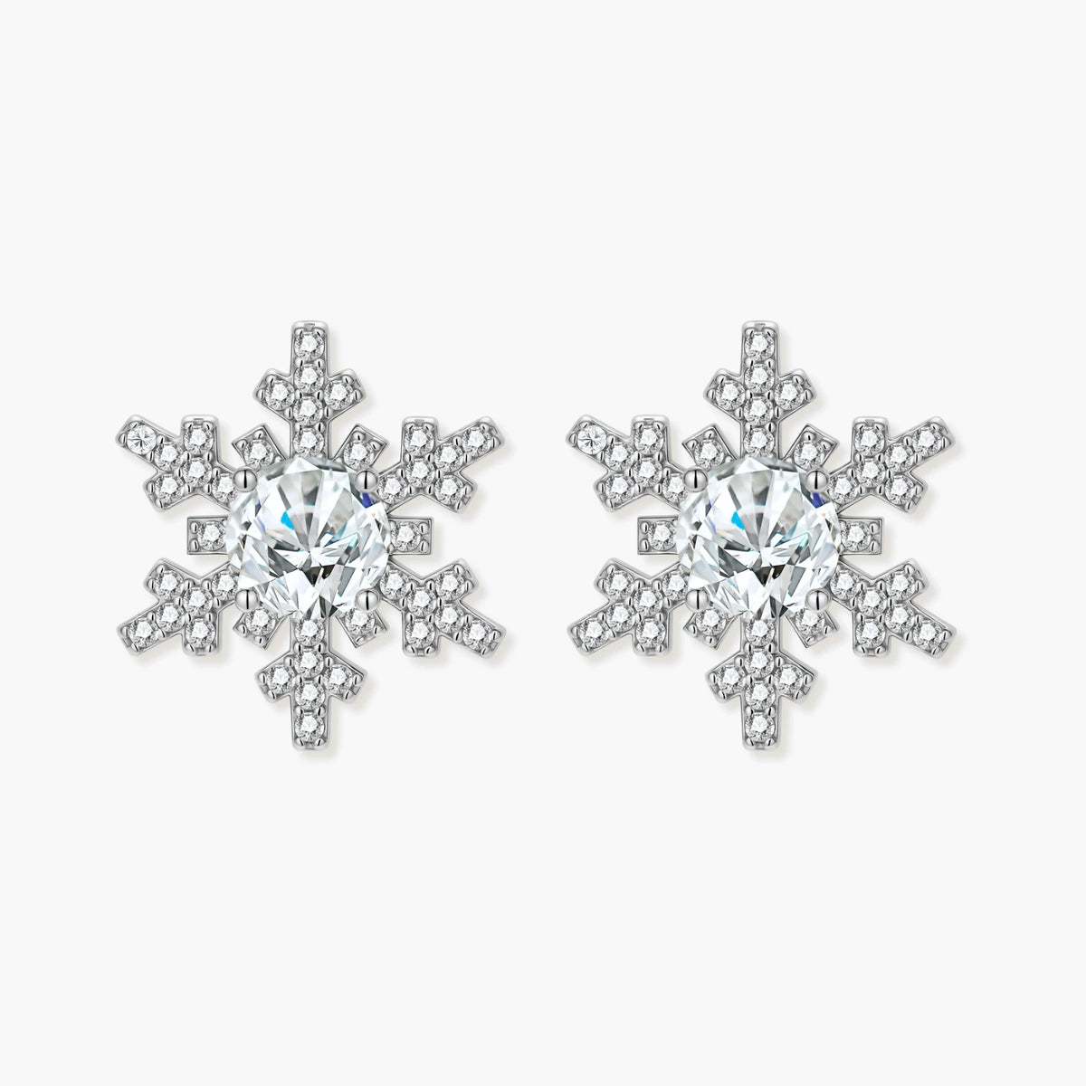 Sterling silver snowflake stud earrings with brilliant moissanite centers and intricate geometric patterns on cream background