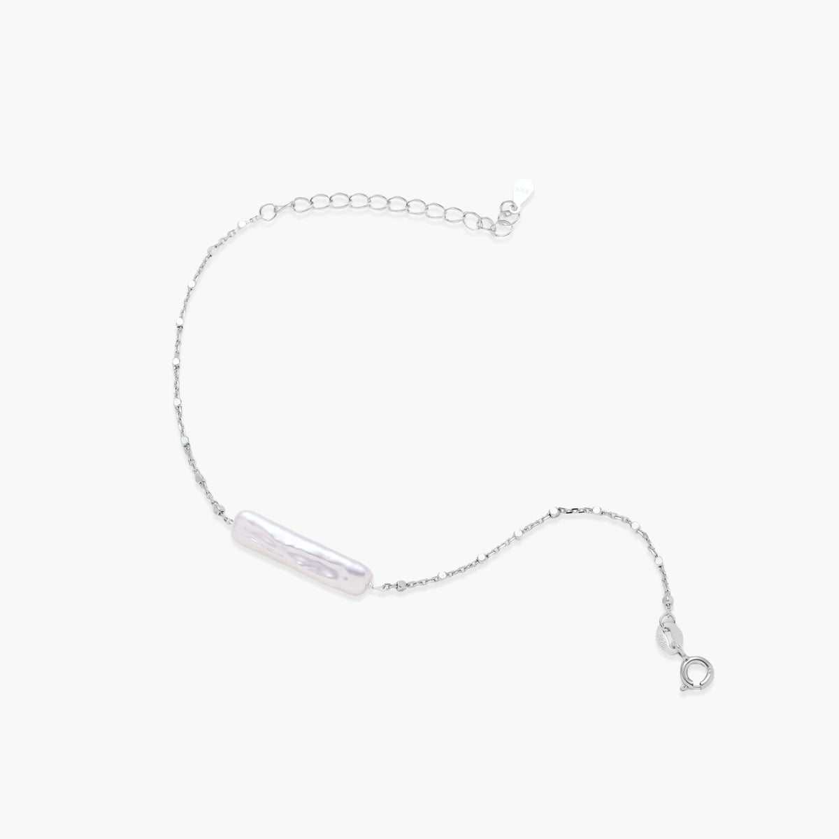 Minimalist bracelet with iridescent baroque pearl on rhodium-plated sterling silver chain against cream background
