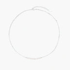 Delicate sterling silver chain necklace with small freshwater pearls arranged in a curved smile arc on cream background.