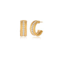 Textured gold huggie hoop earrings with raised ribbed rows creating dimensional sculptural design on cream background