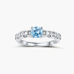 Geometric sterling silver ring with light blue moissanite center stone and square diamond accents on white background