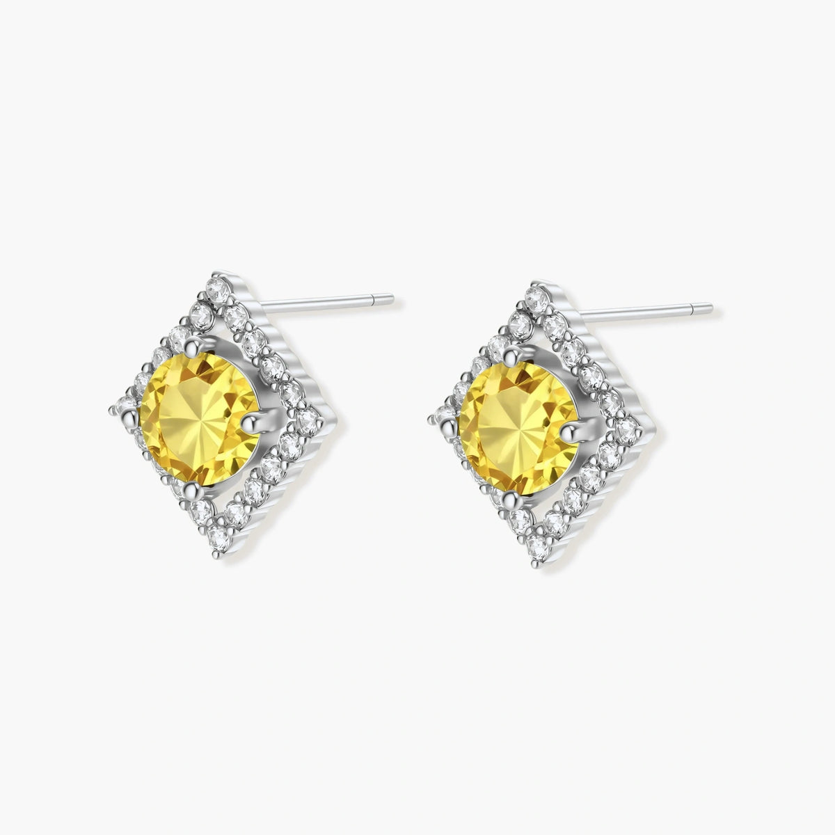 Close-up of diamond-shaped stud earrings with yellow moissanite centers and clear stone halos in sterling silver setting