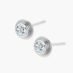 Close-up of sterling silver stud earrings featuring concentric circular frames with brilliant moissanite centers