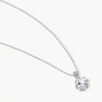 Platinum-plated sterling silver necklace with round clear crystal pendant and decorative bail on neutral background.