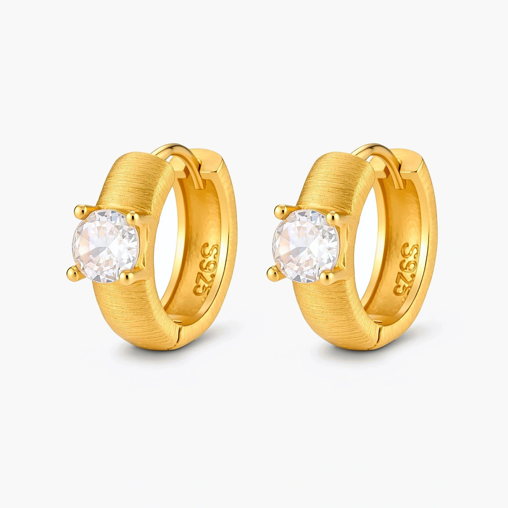18K gold-plated 925 silver huggie hoops with brushed finish and prong-set round CZ solitaire, stamped S925 inside.