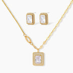Gold-plated jewelry set with rectangular cubic zirconia stones in pave halo settings on cream background