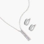 White gold plated necklace with vertical cubic zirconia pendant and matching hoop earrings on neutral background