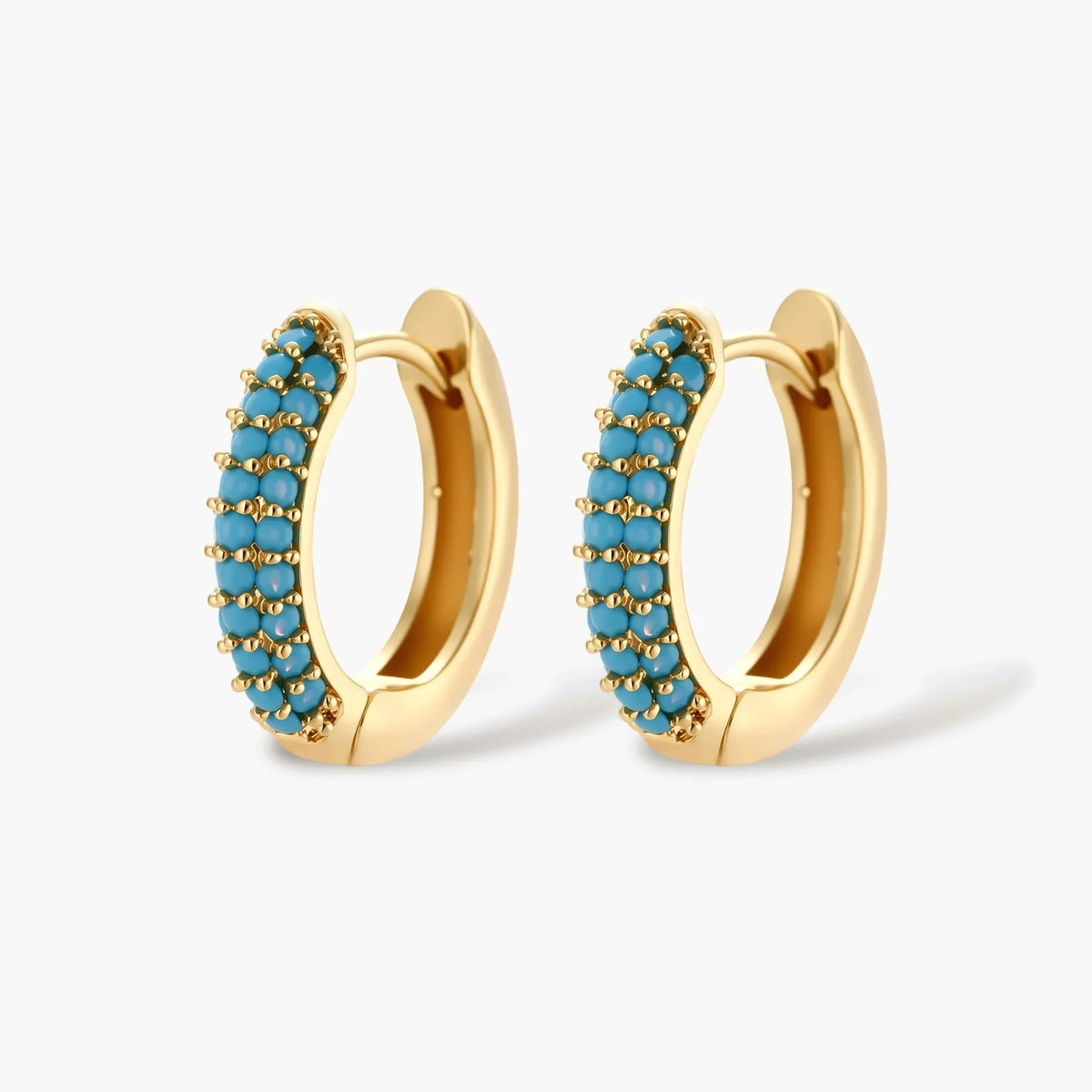 Gold-plated curved necklace and hoop earrings with turquoise cubic zirconia stones on white background.