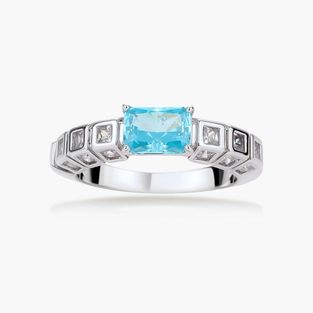 Geometric silver-plated ring with rectangular aqua cubic zirconia center and square crystal details on adjustable band.
