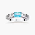 Geometric silver-plated ring with rectangular aqua cubic zirconia center and square crystal details on adjustable band.