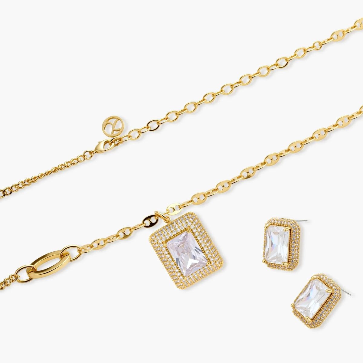 Gold-plated jewelry set with rectangular cubic zirconia stones in pave halo settings on cream background